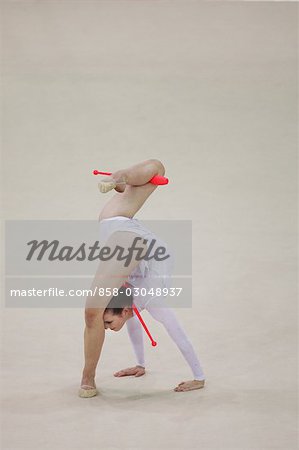 Young woman performing rhythmic gymnastics with clubs