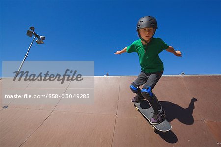 Jeune garçon plongeant avec planche à roulettes de skate park