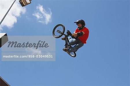 Biker mit seinem Motorrad gegen blauen Himmel springen