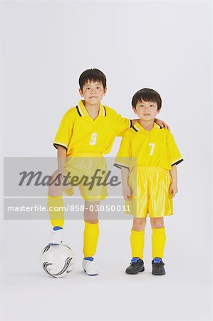 Deux frères, debout avec un pied sur le football