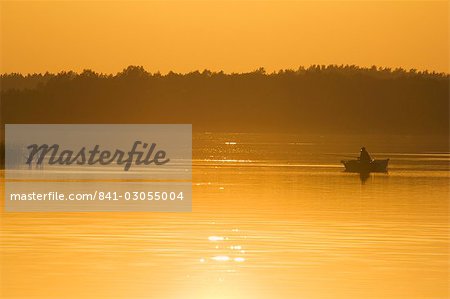 Sunset on lake and fishing boat, Aukstaitija National Park, Lithuania's first national park, Lithuania, Baltic States, Europe