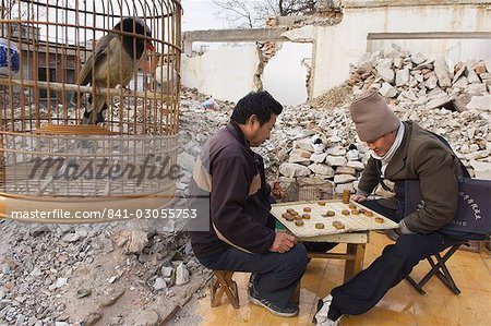 Men playing a board game in a neighbourhood Hutong partially destroyed and marked for demolition, Beijing, China, Asia