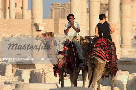 Young men on camels, archaelogical ruins, Palmyra, UNESCO World Heritage Site, Syria, Middle East