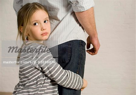 Girl clutching legs of her father