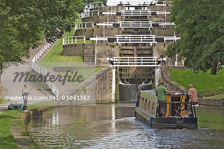 Narrow boat entering the bottom lock of the five lock ladder on the Liverpool Leeds canal, at Bingley, Yorkshire, England, United Kingdom, Europe