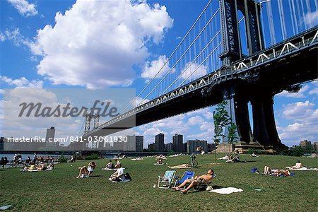 People sunbathing at a park in Brooklyn under the Manhattan Bridge, New York, New York State, United States of America, North America