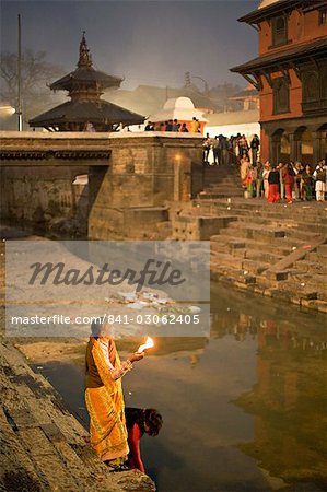 Zwei Frauen darbringen (Puja) vor der Morgendämmerung am Fluss Bagmati außerhalb der Shiva Bügel während der Hindu-fest Shivaratri, Pashupatinath, Kathmandu, Nepal, Asien