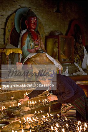 Alte Frau Leuchtlampen Butter in einem kleinen Tempel auf der Nordseite von Susmita oder Bodhnath Stupa, tibetische Neujahr (Lhosar), Kathmandu, Nepal, Asien