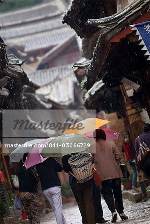 Locals with umbrellas in rain, Lijiang old town, UNESCO World Heritage Site, Yunnan, China, Asia