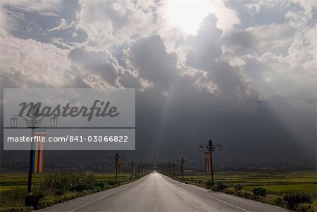 Straße geht in die Ferne mit Sonnenstrahlen und Pagode, Dali, Yunnan, China, Asien