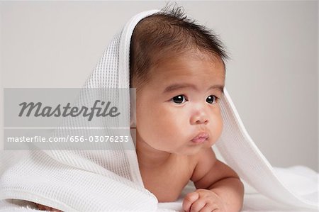 Bébé chinois avec serviette au-dessus de sa tête.