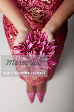 close up of woman wearing pink cheongsam holding purple flower