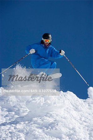 Man in blue jump-suit skiing.