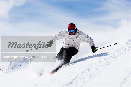 Man in white with red helmet off-piste.
