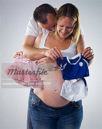 pregnant man and woman with baby clothes