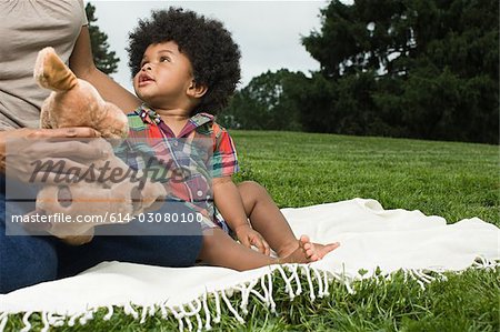 Bébé et la mère sur la couverture dans le parc