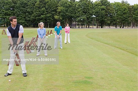 Four golfers on a driving range