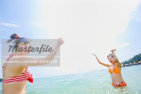 Zwei junge Frauen im Bikini, Spritzwasser