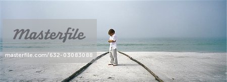 Little boy sulking on beach, arms folded