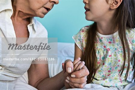Grand-mère et jeune petite-fille main dans la main et de parler, recadrée