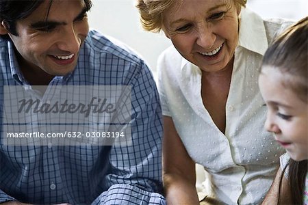 Father, grandmother smiling proudly at little girl