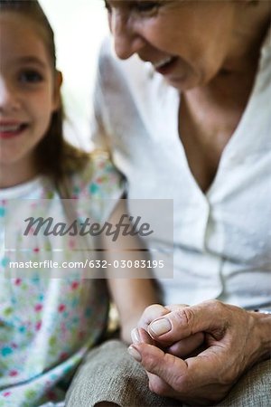 Grandmother and young granddaughter holding hands, close-up