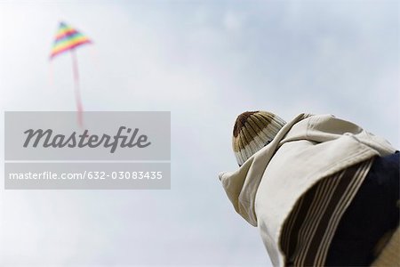 Child watching kite in sky, rear view