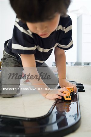 Little boy playing with cars on plastic track