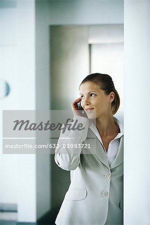 Businesswoman using cell phone, glancing away