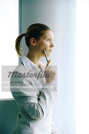 Businesswoman waiting by column, looking away contemplatively