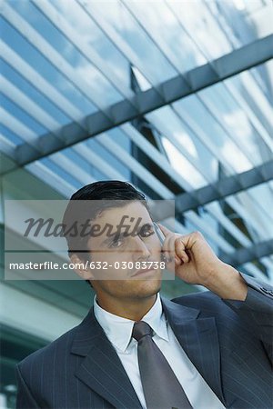 Businessman standing outside office building using cell phone