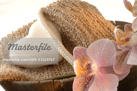 massage belt and heart-shaped soap decorated with flowers in a wooden bowl