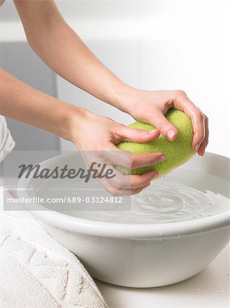 Woman is wringing out a sponge over a washbowl