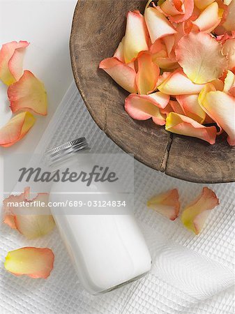 Rose petals in a wooden bowl and a cosmetic bottle