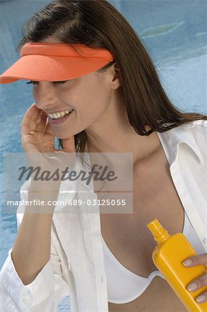 Woman at the swimming pool is applying sunlotion