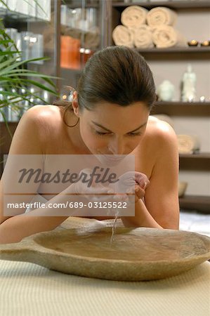 Woman refreshing her face with water from a bowl