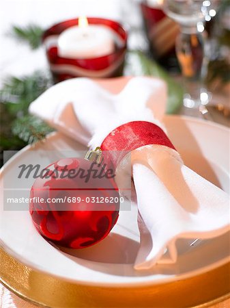 Place cover with a white napkin and a red Christmas tree ball