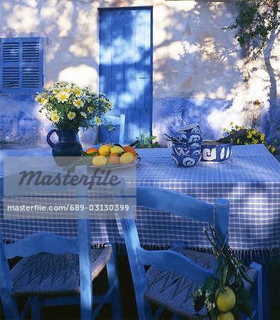 Table bleu et blanc avec un bouquet de marguerites et les oranges et les citrons
