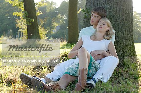 Young couple sitting underneath trea
