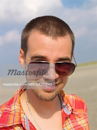 Jeune homme sur la plage avec des lunettes de soleil