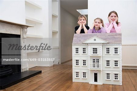 Three children resting on a dollhouse.