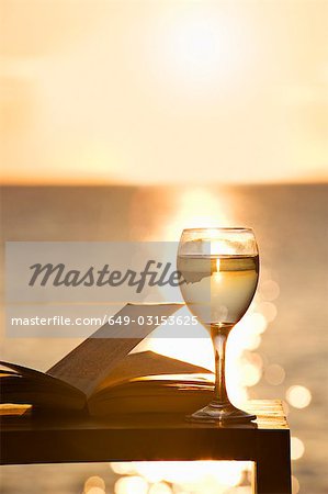 Ein Buch und ein Glas Weißwein bei Sonnenuntergang