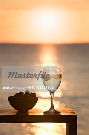 A glass of wine and olives at sunset