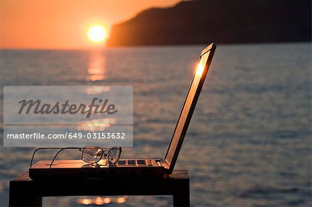 Ein Laptop und Lesebrille bei Sonnenuntergang