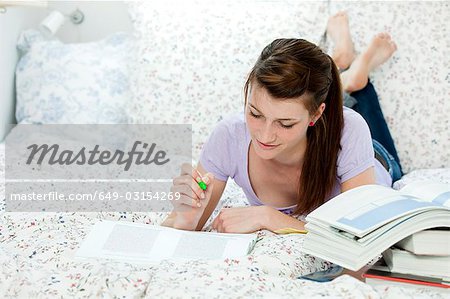 Female student lying in bed, learning