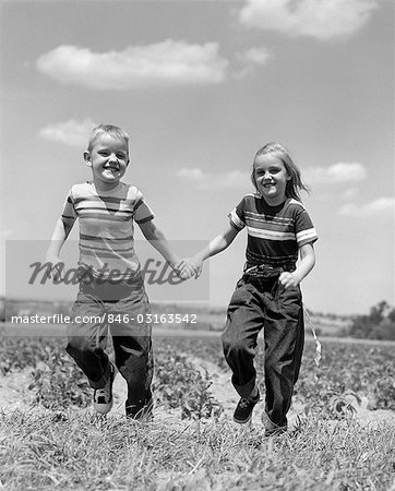 1950s CHILDREN BOY GIRL RUNNING GRASS FIELDS