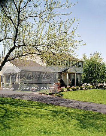 1970s HOUSE WITH BRICK SIDING AND BEIGE SHUTTERS IN THE SPRINGTIME