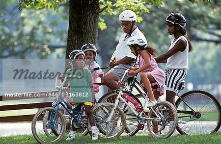 1990s AFRICAN AMERICAN FAMILY BICYCLING WEARING HELMETS