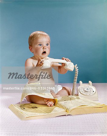 1960s BABY SURPRISED FACIAL EXPRESSION HOLDING TELEPHONE HAND SET OVER YELLOW PAGES PHONE BOOK DIRECTORY