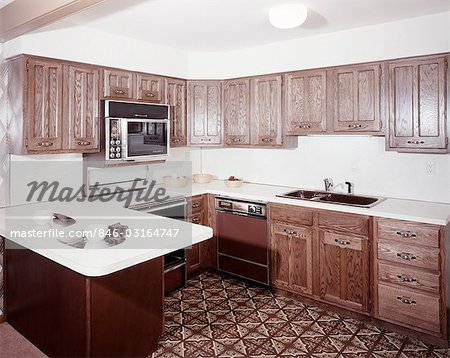1970s KITCHEN WITH DARK WOODEN CABINETS AND A MICROWAVE OVEN OVER THE STOVE